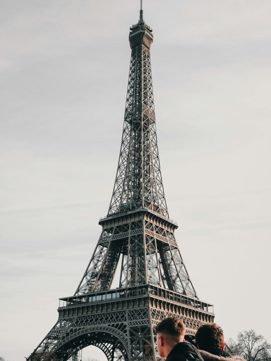 Two travellers looking up at the Eiffel Tower